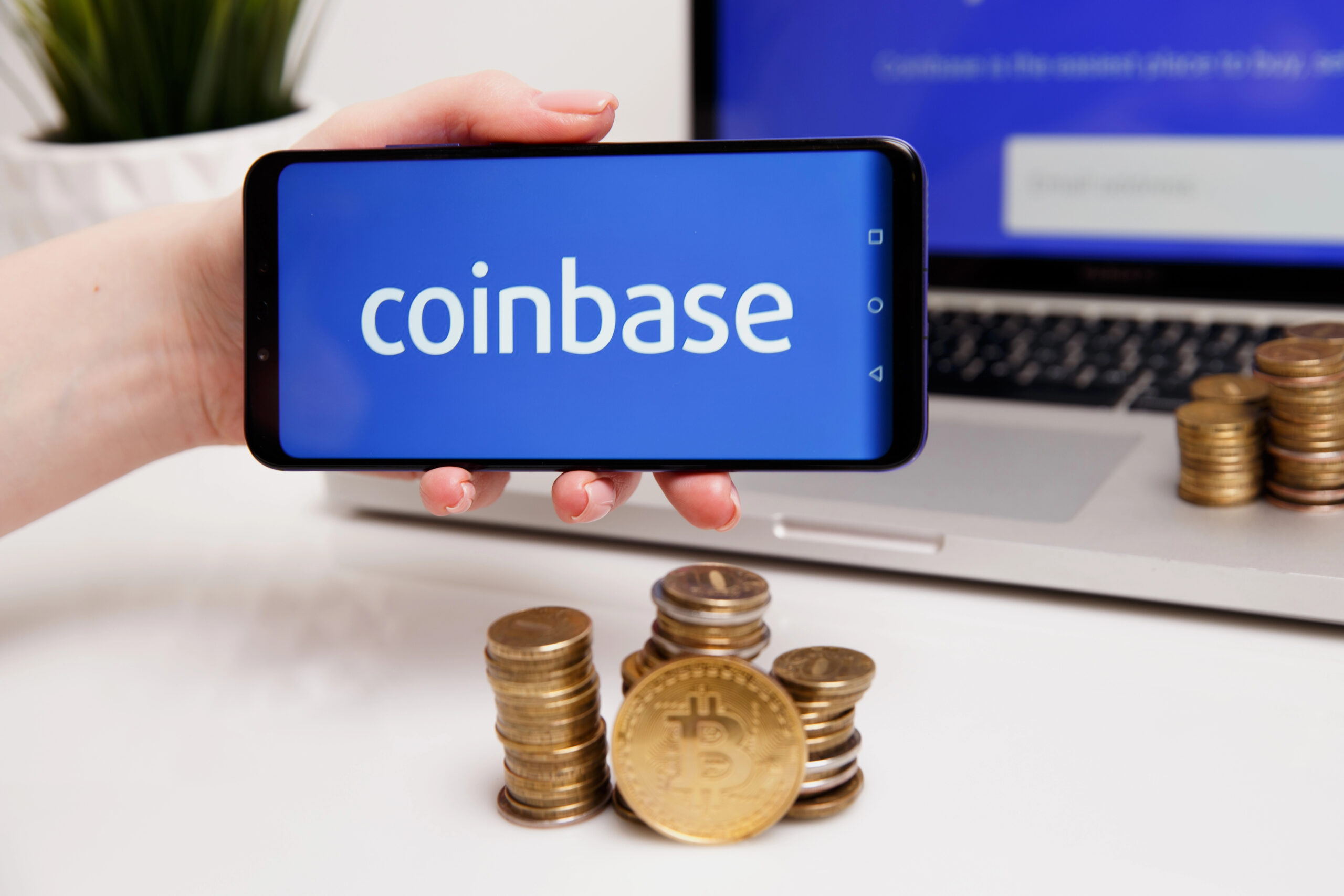 coinbase logo on phone with bitcoins next to computer